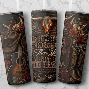 Könnte beinhalten: Ein zylindrischer Becher mit Western-Motiv, bestehend aus einem Cowboyhut, einer Akustikgitarre, Cowboystiefeln, Blumenarrangements und einem Stierschädel. Der Text lautet: IF I'M THE PROBLEM THEN YOU MIGHT BE THE REASON. Der Hintergrund ist dunkles Holz.