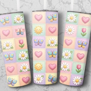 May include: Three pastel-colored tumblers with a patchwork design. Each tumbler features squares with butterflies, hearts, daisies, tulips, and a smiling sun. The tumblers are approximately 8 inches tall.