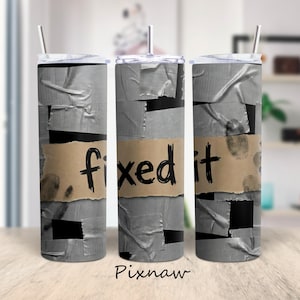 May include: A stainless steel tumbler with a lid and straw. The tumbler is decorated with a design that mimics duct tape and a brown paper label that reads "fixed it" in black lettering. Fingerprints are also visible.