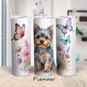 Può includere: Tre bicchieri bianchi in acciaio inossidabile con coperchi e cannucce. Ogni bicchiere presenta un disegno ad acquerello di uno Yorkshire Terrier, farfalle e fiori rosa, viola e blu. La parola "Pixnaw" è stampata in basso.