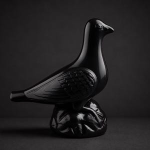Könnte beinhalten: Eine glänzend schwarze Keramikvogel-Skulptur. Der Vogel sitzt auf einem strukturierten Sockel, mit detaillierten Flügel- und Federmustern. Die Skulptur hat ein schlankes, modernes Design, das sich für die Inneneinrichtung eignet.