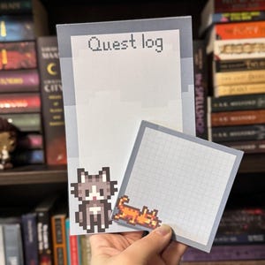 May include: A notepad and sticky note set with pixelated cat graphics. The notepad has the text "Quest log" at the top. The sticky note has a grid pattern. The cat graphics are in shades of gray, brown, and orange.