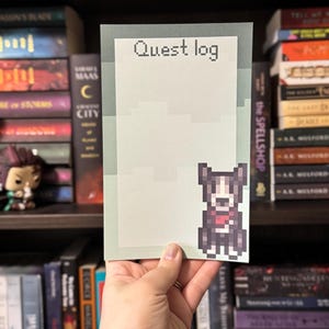May include: A notepad with the text "Quest log" at the top. The notepad has a pixelated dog graphic on the bottom right corner. The notepad is light green and white.