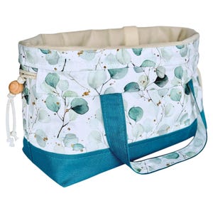 Può includere: Borsa tote in tessuto con sfondo bianco e motivo di foglie di eucalipto verdi e dettagli dorati. La base e i manici sono color turchese. Ha una chiusura con coulisse e una perla di legno.