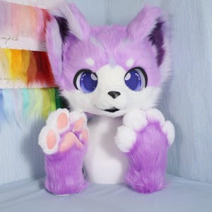 May include: A purple and white furry animal head and paws. The head has large blue eyes and a black nose. The paws have pink paw pads. The fur is a mix of purple and white. The product is likely a costume or cosplay item.