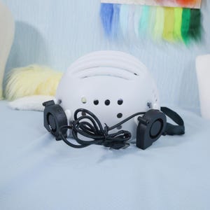 Adjustable skull helmet base laid out with cosplay tools and foam blocks to show compatibility with different build styles. Ideal for animal, fantasy, or mascot characters, this fursuit insert offers both functionality and comfort. Optional USB fans can be added for airflow, and the plastic shell is strong enough to hold sculpted foam or layered fabric shells with ease.