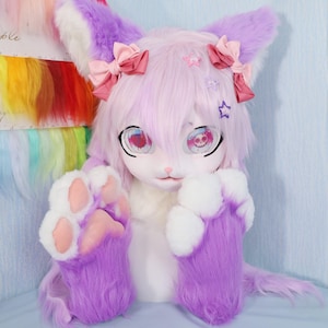 May include: A plush, furry, purple and white fursuit head and paws. The head has large, expressive eyes with a skull design, pink bows, and star accents. The paws are detailed with pink paw pads.