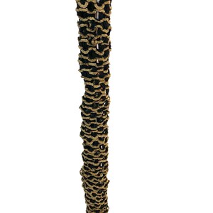 May include: A vertical close-up of a decorative item with a repeating pattern. The item is a column of alternating black and tan, looped, textured material. The background is plain white.