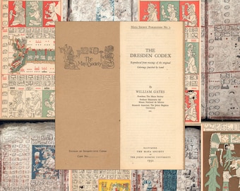 Può includere: Un libro aperto intitolato "The Dresden Codex" di William Gates, pubblicato da The Maya Society nel 1932. Il libro è circondato da pagine con glifi e illustrazioni Maya in rosso, verde e marrone.