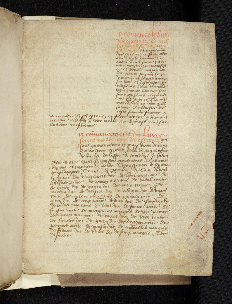 May include: An open book with aged, yellowed pages. The text is handwritten in red ink, with a script that appears to be from a historical period. The book is open to a page with a detailed script.