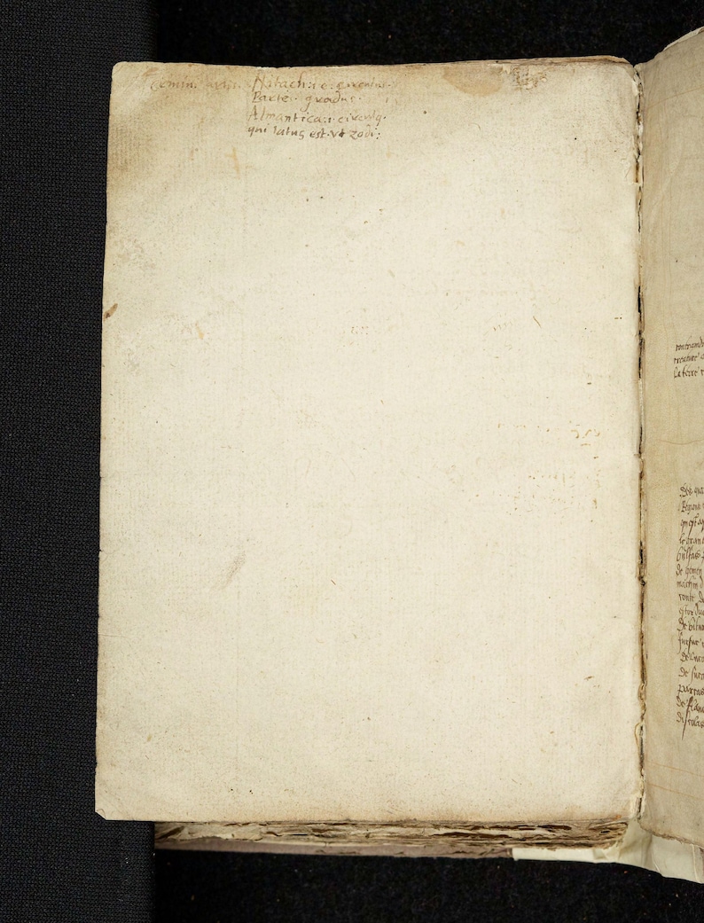 May include: Open book with aged, off-white pages. The left page has faded handwritten text in black ink at the top. The right page has more text in a similar style. The book's edges are worn, suggesting age and use.