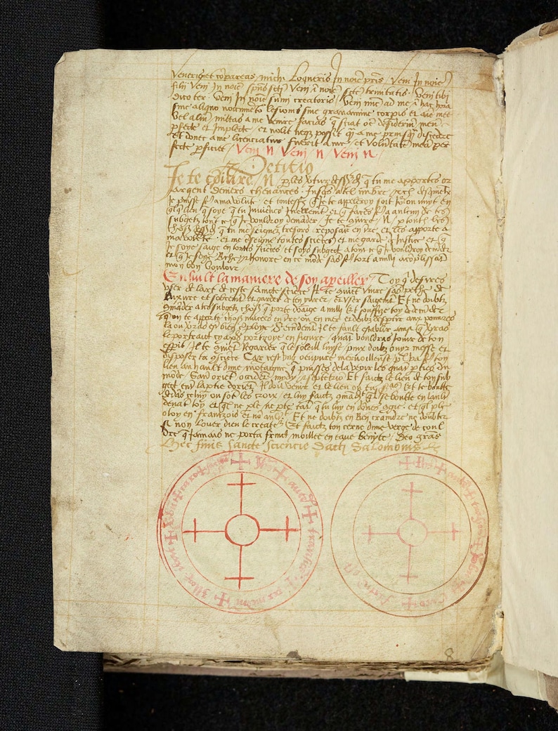 May include: Open book with aged, cream-colored pages. Handwritten text in black and red ink fills the pages, with circular diagrams featuring crosses. The book appears to be an antique manuscript.