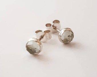 May include: A pair of silver stud earrings with light green round gemstones.