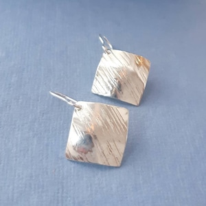 Peut inclure: Une paire de boucles d'oreilles en argent de forme carrée avec une surface texturée.