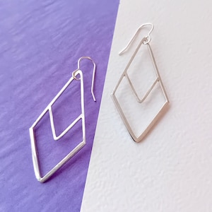 Peut inclure: Une paire de boucles d'oreilles géométriques en argent de forme losange. Les boucles d'oreilles ont un design à double couche.