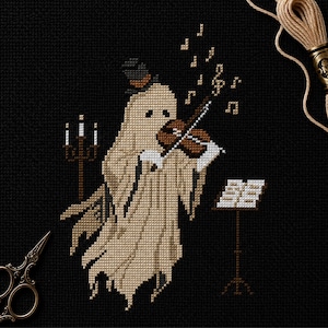 May include: A cross-stitch pattern on black fabric featuring a beige ghost wearing a top hat and playing a brown violin. Beside the ghost is a brown candelabra and a music stand with sheet music. Musical notes float above the ghost's head.