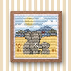 May include: Cross-stitch artwork of two gray elephants in a sunny landscape with mountains and a heart. The artwork is framed in a wooden frame and set against a striped background. The elephants are in a field of yellow grass.