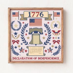 May include: A framed cross-stitch featuring patriotic symbols. The design includes the year "1776", American flags, the Liberty Bell, stars, laurel wreaths, and the text "Declaration of Independence". The color palette is red, white, blue, and beige.
