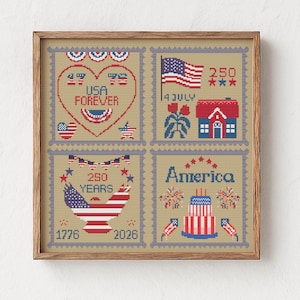 May include: A framed cross-stitch artwork featuring patriotic imagery. The design includes four squares with American flags, a heart with "USA FOREVER," a house, and the word "America." The color palette is red, white, and blue.