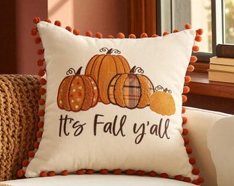 May include: Cream-colored square throw pillow with embroidered pumpkins in shades of orange and brown. The pillow has a pom-pom trim and the text "It's Fall y'all" in black script.
