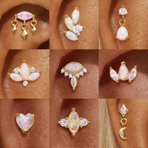 Puede incluir: Una colección de pendientes dorados con detalles de ópalo y cristal. Los diseños incluyen gotas, colgantes y formas florales. Los pendientes se muestran en primeros planos, destacando los detalles y las texturas.