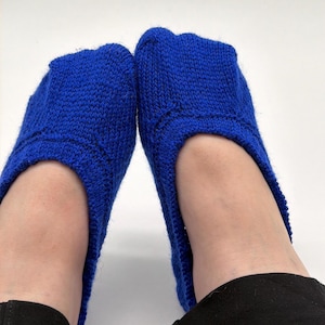 May include: A pair of vibrant royal blue knit socks with a low-cut ankle design. The socks feature a textured, hand-knitted stitch pattern throughout the body and a reinforced edge around the opening, providing a snug fit around the foot.