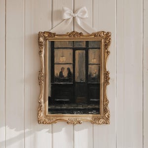 May include: A rectangular painting in an ornate gold frame featuring a dark, moody scene of two figures sitting inside a dimly lit cafe storefront. A large, white satin ribbon bow is attached to the top centre of the frame for hanging.