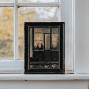 May include: A framed oil painting depicting a dark, moody street scene at night. The artwork shows a storefront with large windows, illuminated by warm interior lights, where two figures are seated at a table. The frame is black and rectangular.