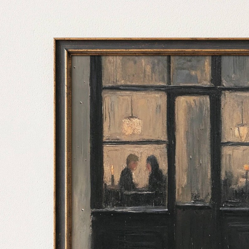 May include: A framed oil painting depicting a dark storefront exterior with large glass windows. Inside, two figures sit at a table illuminated by warm, glowing pendant lights and a candle. The scene features a black frame with gold trim details.
