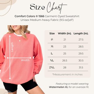 May include: A coral sweatshirt with a size chart. The chart shows measurements in inches for sizes S to 2XL. The text reads "Comfort Colors 1566 Garment-Dyed Sweatshirt." The model is wearing a Watermelon XL for an oversize fit.