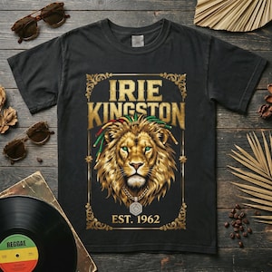 May include: Black t-shirt featuring a detailed illustration of a lion with dreadlocks, a gold chain, and the text "IRIE KINGSTON EST. 1962" in gold lettering. The design is framed with ornate gold borders.