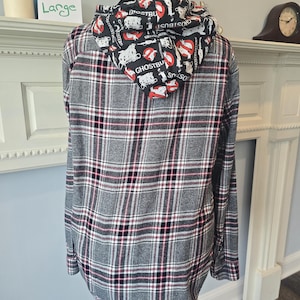 May include: A gray, black, and red plaid flannel shirt with a Ghostbusters-themed hood. The hood features a black background with white and red Ghostbusters logos. The shirt is displayed on a mannequin and labeled "Large".