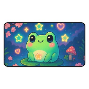 Puede incluir: Alfombrilla de ratón rectangular con una rana de dibujos animados sentada en una hoja de nenúfar. La rana es verde con mejillas rosas y una estrella en la barriga. El fondo incluye estrellas, corazones y una seta brillantes.