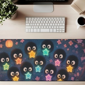 May include: A rectangular desk mat featuring a whimsical design with cartoon-like creatures holding glowing star shapes. The mat has a dark blue background with pink floral accents and a paper lantern.