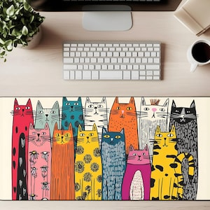 Puede incluir: Alfombrilla de escritorio rectangular con una ilustración colorida de gatos estilizados. Los gatos son de varios colores, incluyendo rojo, rosa, naranja, amarillo, azul y negro, con patrones y expresiones únicas. El fondo es de color beige claro.