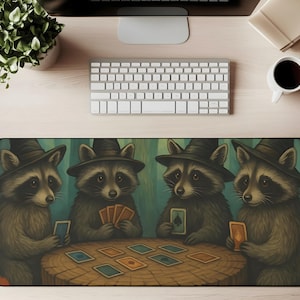 Op de afbeelding: Een rechthoekige bureaumat met een grillige illustratie van vier wasberen met heksenhoeden, die kaarten spelen rond een houten tafel. De achtergrond is een boslandschap met groene en blauwe tinten. De mat is ontworpen om het bureaublad te beschermen.