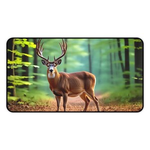 Könnte beinhalten: Rechteckiges Mauspad mit einem majestätischen Hirsch mit großem Geweih in einem Wald. Das braune Fell des Hirsches hebt sich von den grünen Bäumen und einem Weg mit Blättern ab. Das Mauspad hat einen schwarzen Rand.