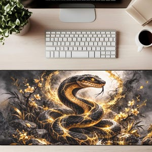 Könnte beinhalten: Schwarze und goldene Schreibtischunterlage mit einem Schlangenmuster. Das Bild zeigt eine detaillierte Illustration einer Schlange mit leuchtenden Goldmustern, vor einem rauchigen Hintergrund mit floralen Elementen. Die Matte dient zum Schutz des Schreibtisches.