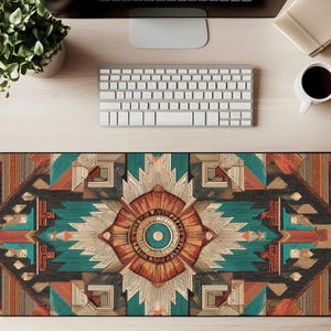 Puede incluir: Una alfombrilla de escritorio rectangular con un patrón geométrico en tonos turquesa, naranja, marrón y negro. El diseño presenta un motivo central en forma de flor y formas simétricas. La alfombrilla está diseñada para proteger la superficie del escritorio.