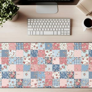 Könnte beinhalten: Eine rechteckige Schreibtischunterlage mit Patchwork-Design. Die Matte zeigt Quadrate mit rosa, blauen und weißen Mustern, darunter Blumendrucke, Tupfen und Vichy-Karo. Die Matte soll die Schreibtischoberfläche schützen.
