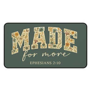 May include: A rectangular, dark green decorative item with rounded corners. The word "MADE" is displayed in large, floral-filled letters, above "for more" in cursive script. The text "EPHESIANS 2:10" is at the bottom.