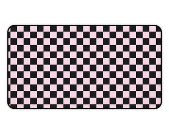 May include: A rectangular mat with a black and pink checkerboard pattern. The mat has rounded corners and a simple, bold design. The alternating squares create a visually striking effect.