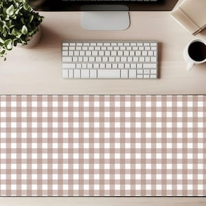 Puede incluir: Alfombrilla de escritorio rectangular con un patrón de cuadros vichy marrón y blanco. La alfombrilla tiene un borde negro. Un teclado, un monitor, una taza de café y una planta son visibles sobre una superficie de madera clara.