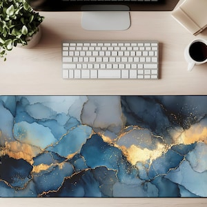 May include: A rectangular desk mat with a blue and gold abstract design. The mat features a watercolor-like pattern with shades of blue and gold, creating a marbled effect. The mat is designed to accommodate a keyboard and mouse, enhancing the workspace.