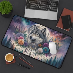 May include: A rectangular mouse pad featuring a wolf with a full moon backdrop, surrounded by colorful flowers and a dreamcatcher. The design incorporates shades of purple, blue, and pink, with a black border. A white mouse and a laptop are also visible.