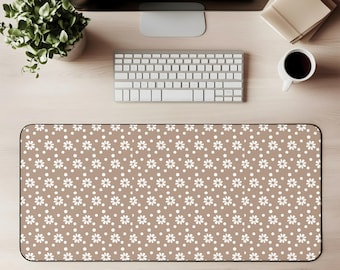 Puede incluir: Alfombrilla de escritorio rectangular con un patrón repetido de margaritas y puntos blancos sobre un fondo marrón. La alfombrilla está diseñada para proteger la superficie del escritorio y proporcionar una superficie lisa para el ratón y el teclado.