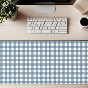 May include: A blue and white gingham desk mat. The mat is rectangular with rounded corners and a black border. A keyboard, computer monitor, coffee cup, and plant are visible on the desk.