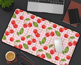Può includere: Tappetino per scrivania rettangolare con un motivo di ciliegie rosse e foglie verdi su uno sfondo a quadretti rosa e bianchi. Un mouse per computer è appoggiato sul tappetino, con un laptop e un taccuino visibili.