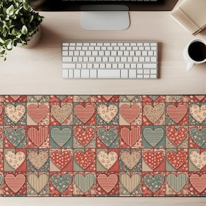 Puede incluir: Una alfombrilla de escritorio rectangular con un diseño de patchwork de corazones en varios patrones y colores, incluyendo estampados rojos, turquesa y florales. La alfombrilla está diseñada para proteger la superficie del escritorio y proporcionar un espacio de trabajo cómodo.