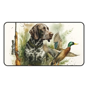 May include: Watercolor illustration of a hunting scene featuring a German Shorthaired Pointer, a rifle, and a flying duck. The dog has brown and white speckled fur and a green collar. The duck has brown, green, and blue feathers. The rifle is brown.